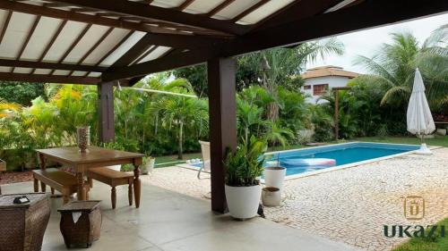 a patio with a table and a swimming pool at Casa paraiso in Camaçari