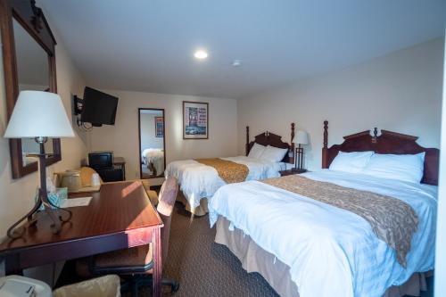 a hotel room with two beds and a desk at Watkins Motel in Watkins Glen