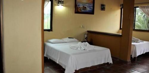 a bedroom with two beds with white sheets at Posada Las Flores in Los Ayala