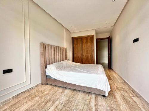 a bedroom with a bed with white sheets and wooden floors at Rez de jardin avec piscine privée in Casablanca