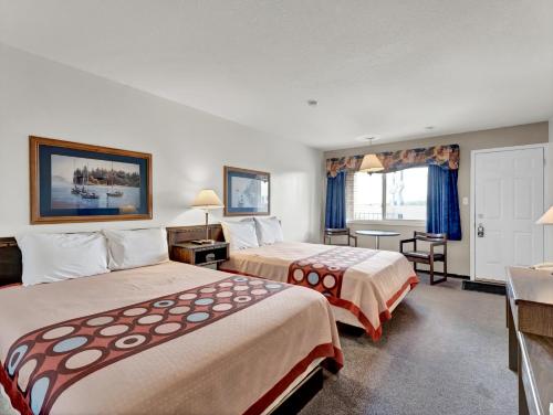 a hotel room with two beds and a desk at Ranchmen Motel in Medicine Hat
