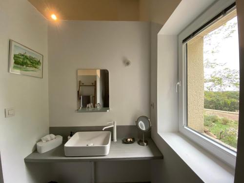 a bathroom with a sink and a window at Les Esplanes in La Garde-Adhémar