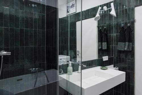 a black tiled bathroom with a sink and a mirror at Marktplatz-Residenz - 110 m vom Traunsee in Gmunden
