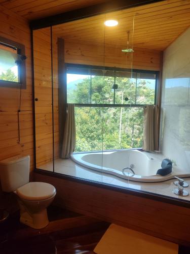 a bathroom with a tub and a toilet and a window at Pousada Mirante do Céu in Visconde De Maua