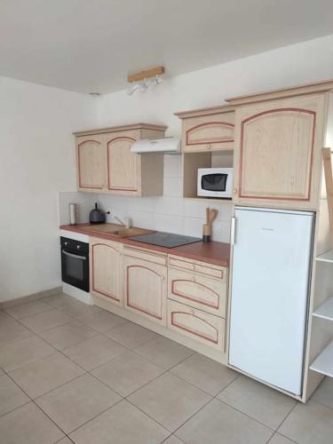 une cuisine avec des armoires en bois et un réfrigérateur blanc dans l'établissement Maison charmante à proximité de Luçon, à Les Magnils-Reigniers