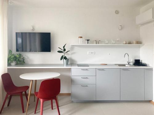 a white kitchen with red chairs and a table at STUDIO GREENHOUSE in Tolmin