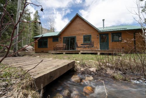 a log cabin with a bridge in front of it at Beyul Retreat in Meredith