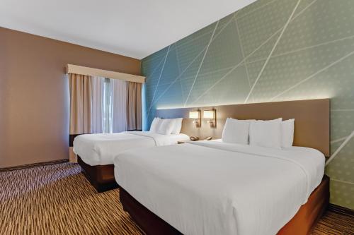 a hotel room with two beds with white sheets at Comfort Suites Murfreesboro Shopping District in Murfreesboro