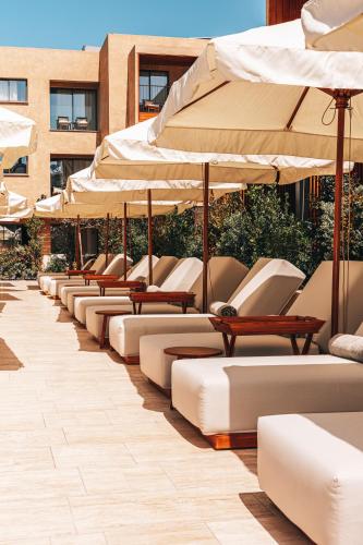 a row of lounge chairs and umbrellas on a patio at M Boutique Hotel - Designed for Adults in Paphos City