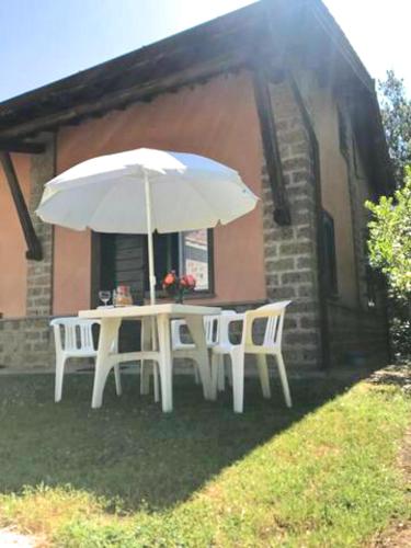 a white table and chairs with an umbrella at Montecasciano - Oleandro in Capranica