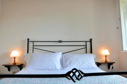a bed with white pillows and two lamps on tables at Montecasciano - Girasole in Capranica
