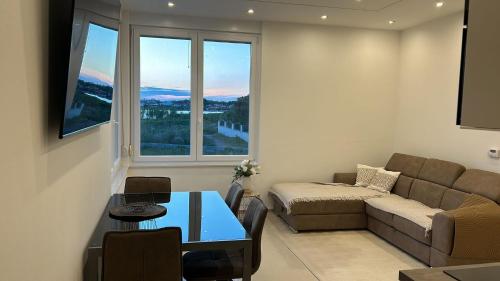 een woonkamer met een bank, een tafel en een raam bij Apartments Villa Prima in Privlaka