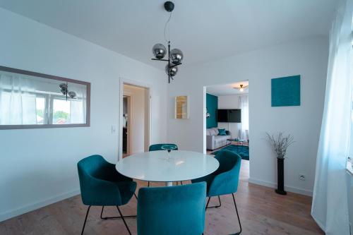 a dining room with a white table and blue chairs at Zentral gelegene Ferienwohnung Solingen - Ohligs in Solingen