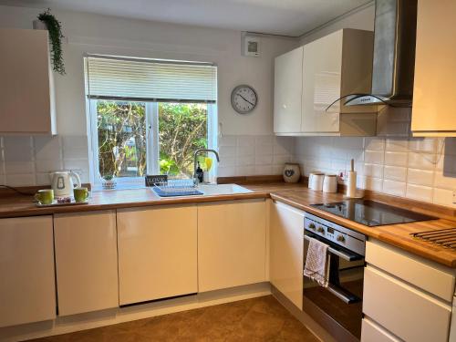 uma cozinha com armários brancos e uma janela em Balcony Breeze - Reading City Centre em Reading
