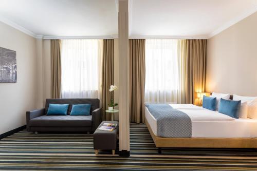 um quarto de hotel com uma cama e uma cadeira em Leonardo Hotel Budapest em Budapeste