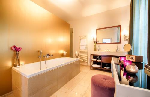 baño grande con bañera y espejo en Alden Suite Hotel Splügenschloss Zurich en Zúrich