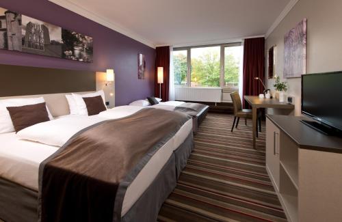 una camera d'albergo con due letti e una televisione di Leonardo Hotel Mönchengladbach a Mönchengladbach