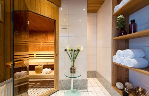 un baño con toallas y un jarrón de flores sobre una mesa en Leonardo Hotel Mönchengladbach, en Mönchengladbach