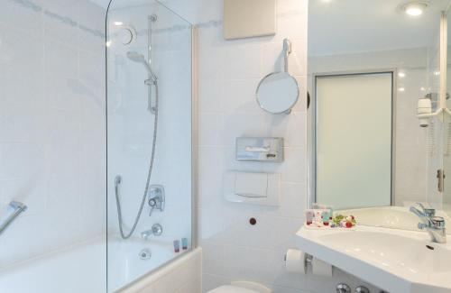 y baño con ducha, aseo y lavamanos. en Leonardo Royal Hotel Baden- Baden en Baden-Baden