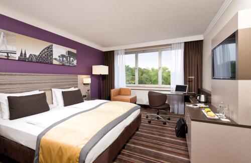 um quarto de hotel com uma cama grande e uma secretária em Leonardo Royal Hotel Köln - Am Stadtwald em Colónia