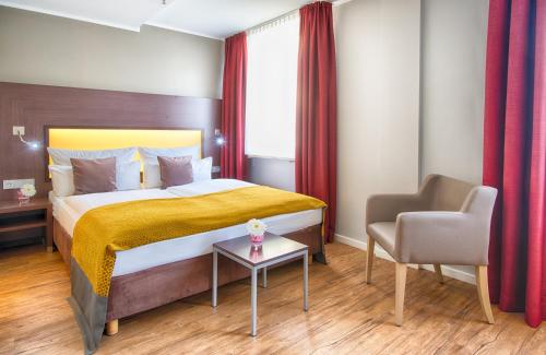 a hotel room with a bed and a chair at Leonardo Hotel München City Center in Munich