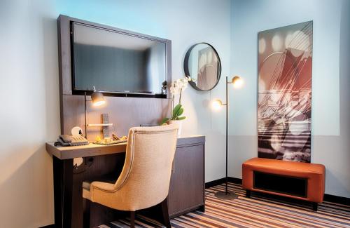 een kamer met een bureau met een stoel en een spiegel bij Leonardo Boutique Hotel Düsseldorf in Düsseldorf