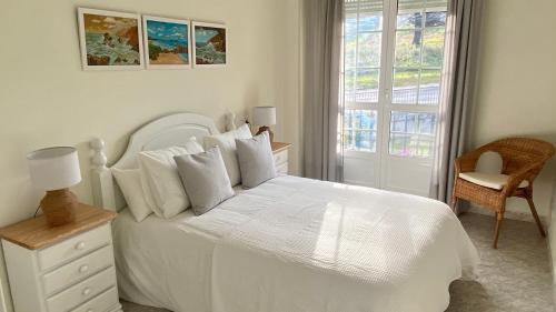 a white bedroom with a white bed and a window at Casa en 1ª línea del mar - House on Sea Front Valdoviño in Valdoviño