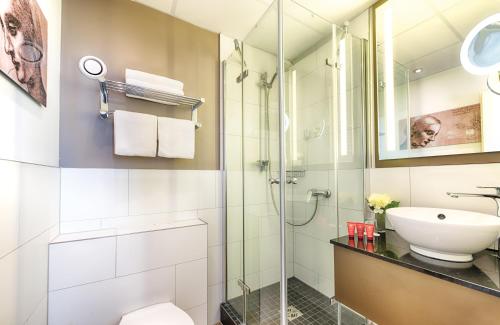 een badkamer met een douche, een toilet en een wastafel bij Leonardo Hotel Heidelberg City Center in Heidelberg