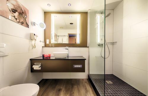 a bathroom with a sink and a shower at Leonardo Hotel Mannheim City Center in Mannheim