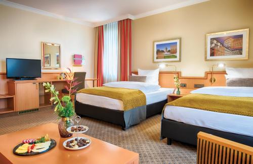 um quarto de hotel com duas camas e uma televisão em Leonardo Hotel Mannheim City Center em Mannheim