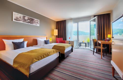 Cette chambre comprend deux lits et un bureau. dans l'établissement Leonardo Hotel Heidelberg City Center, à Heidelberg