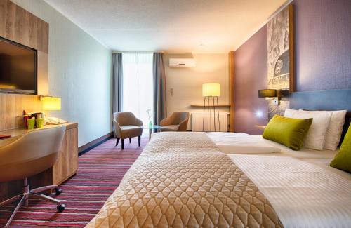 a hotel room with a large bed and a desk at Leonardo Hotel Wolfsburg City Center in Wolfsburg