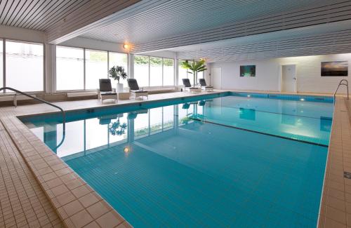 a large swimming pool with blue water in a building at Leonardo Hotel Wolfsburg City Center in Wolfsburg