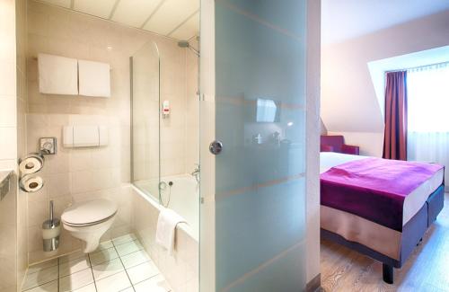 a bathroom with a bed and a toilet and a shower at Leonardo Hotel Mannheim-Ladenburg in Ladenburg