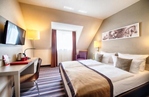 a hotel room with a bed and a desk and a television at Leonardo Hotel Mannheim-Ladenburg in Ladenburg