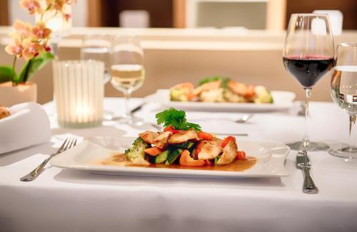 a table with two plates of food and glasses of wine at Leonardo Boutique Hotel Rigihof Zurich in Zürich