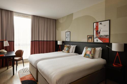 a hotel room with two beds and a desk at Hotel Indigo Newcastle by IHG in Newcastle upon Tyne