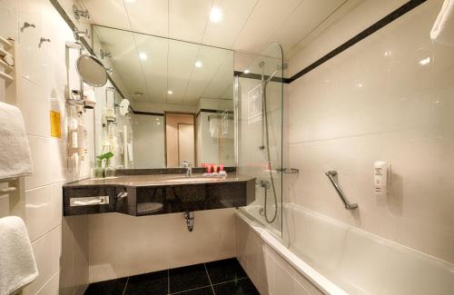 a bathroom with a sink and a shower at Leonardo Hotel Hannover in Hannover