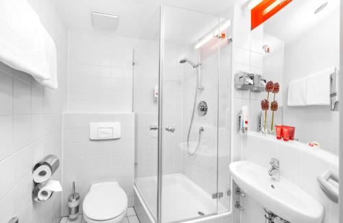 a bathroom with a shower and a toilet and a sink at Leonardo Hotel Nürnberg in Nuremberg