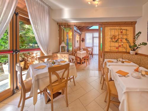 a dining room with tables and chairs and windows at Hotel Garni La Vigna - Adult Friendly in San Michele allʼAdige