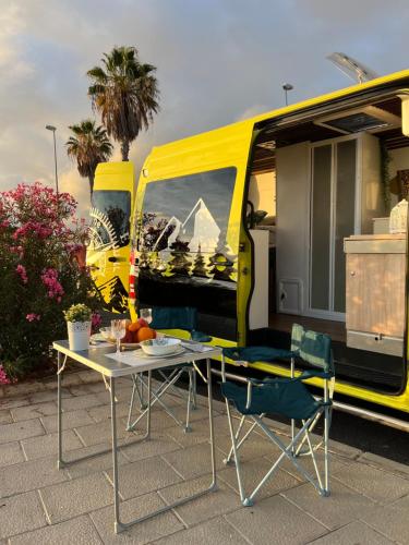 El Guincho的住宿－On Road- feel freedom with campervan!，黄色面包车前面的桌椅
