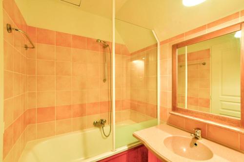une salle de bain avec un lavabo, une baignoire et un miroir dans l'établissement La résidence du Lac - maeva Home - Appartement 2 pièces 5 personnes - Sélection MAE-4461, à Monflanquin