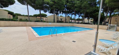 - une piscine avec 2 chaises longues à côté dans l'établissement Studio Cap d'Agde avec piscine, tennis entièrement rénové, au Cap d'Agde