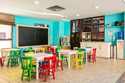a classroom with tables and colorful chairs and a chalkboard at Studio à beira mar - Hotel Jurerê Beach Village in Florianópolis