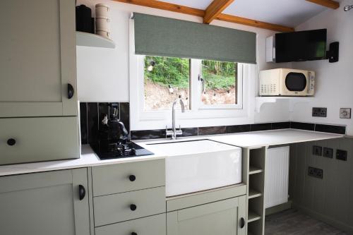 a kitchen with white cabinets and a sink and a window at Wildwood Quarry Retreat in Mold