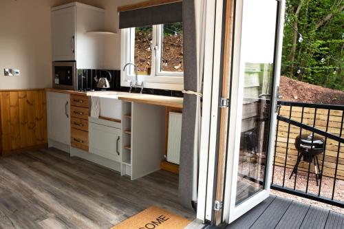 a kitchen with white cabinets and a sliding glass door at Wildwood Quarry Retreat in Mold