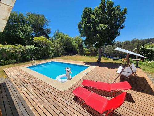 a swimming pool with two chairs and a hammock on a deck at Casa Algarrobo antiguo in Algarrobo