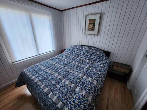 a bedroom with a bed with a blue comforter and a window at Casa Algarrobo antiguo in Algarrobo