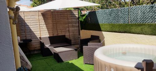 een hot tub in de achtertuin met een stoel en een paraplu bij Maison T2 proche mer jardin spa jacuzzi et parking in Six-Fours-les-Plages