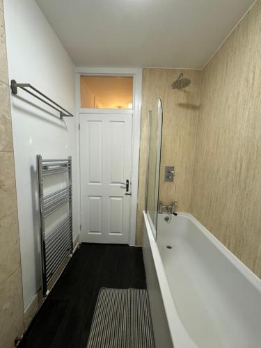a bathroom with a white tub and a door at Manor Court in London